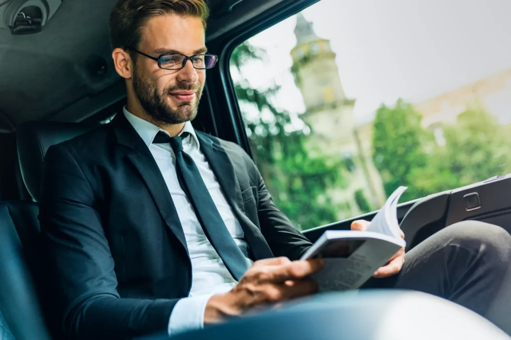 young-businessman-sitting-inside-charter bus rental and reading